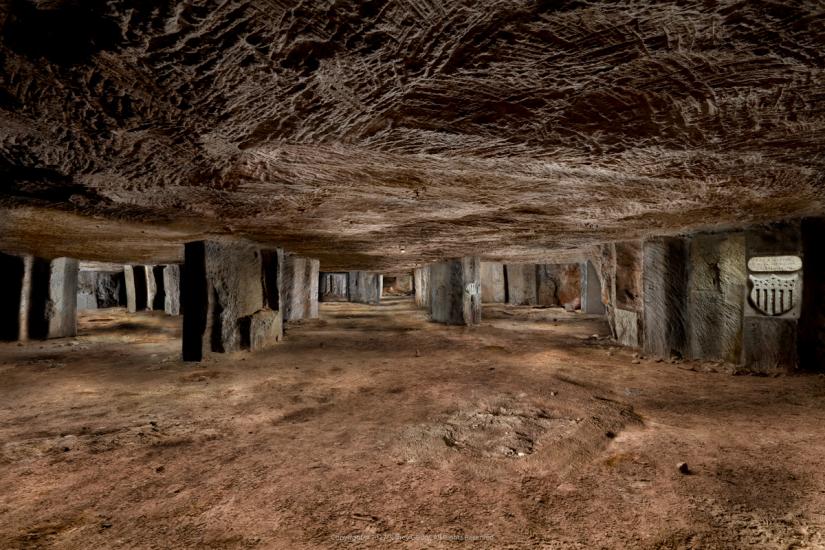 Expansive view underground with stone support columns and carvings visible. 