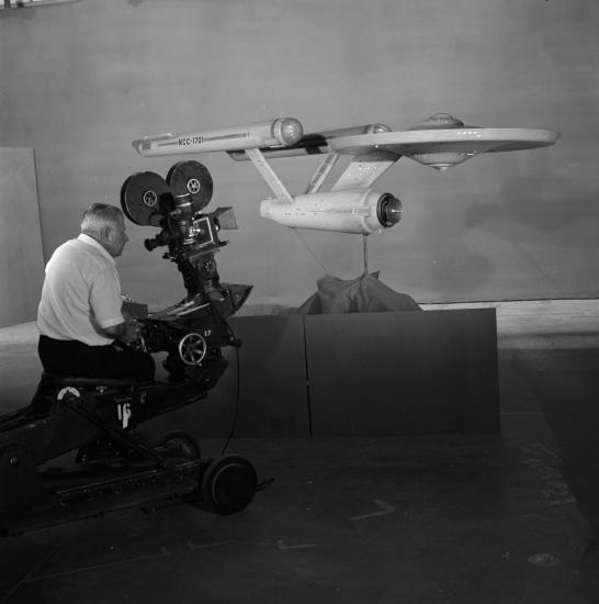 A person films the Star Trek Starship Enterprise studio model in front of a green screen.