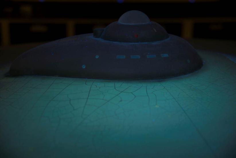 A partial view of the top portion of the Enterprise Studio Model under special lighting. Cracks can be seen on the saucer of the spacecraft from age.