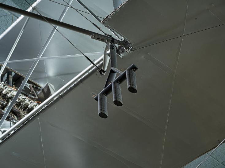 Black metal three-pronged apparatus hanging from metal Voisin Type 8 aircraft