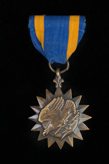 Bronze sunburst medal with eagle holding lightning bolts on blue silk ribbon with gold stripes