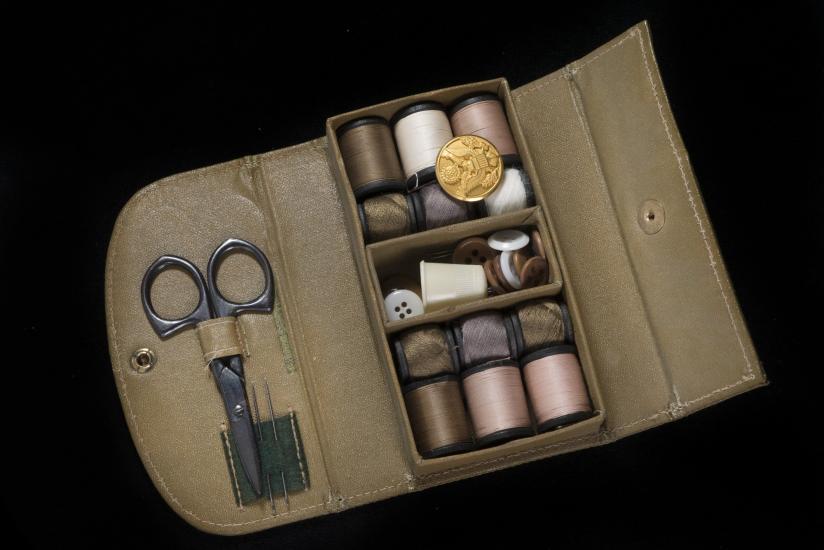 Rectangular box with thread spools, needles, buttons, and scissors