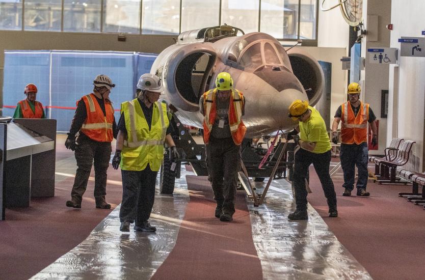 The forward fuselage of the Lockheed U-2 aircraft is moved by staff and contractors.