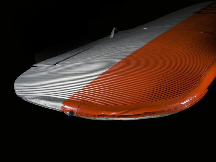 Close up view of a silver and orange painted wing of an airplane.