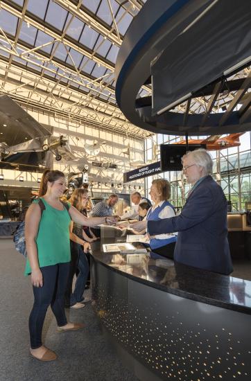 Visitors being helped by the Welcome Center in the Boeing Milestones of Flight Hall