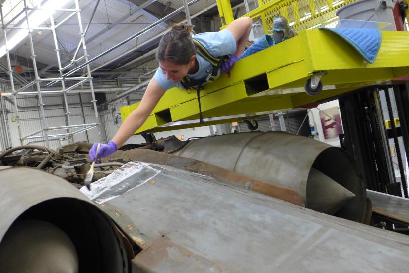 Conservator hovers above aircraft to clean it. 