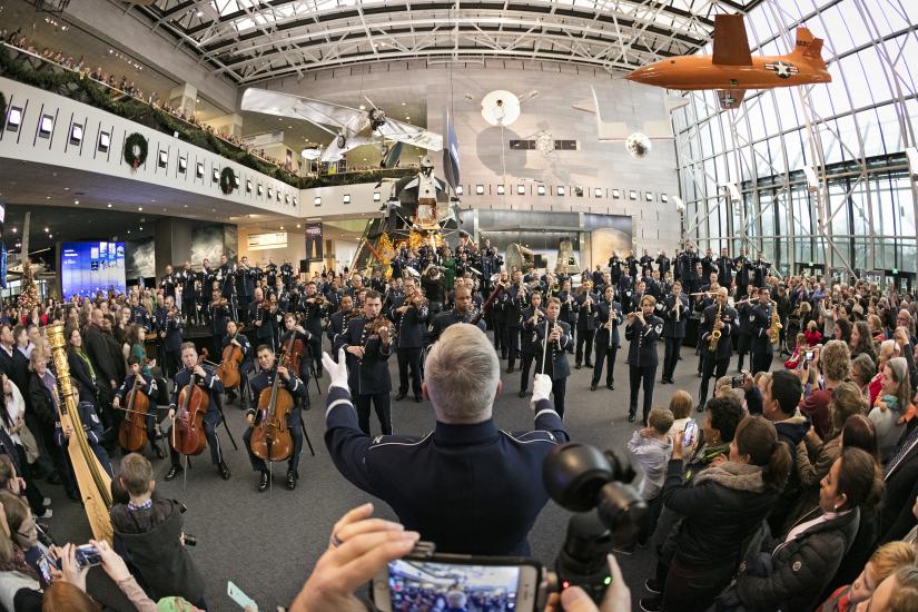 The U.S. Air Force Band performs in the museum with a large crowd of viewers in attendance.