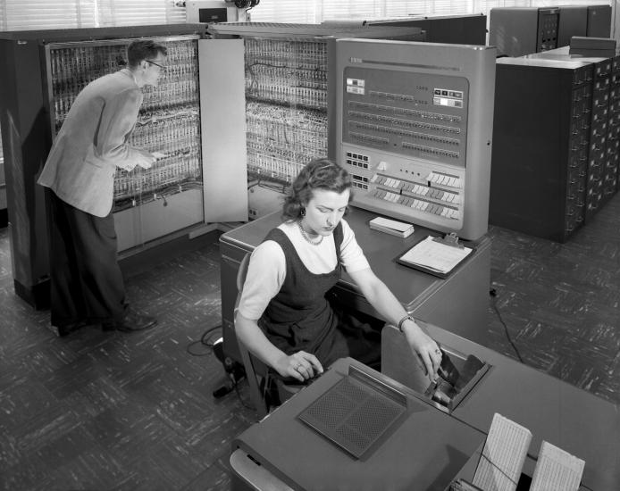 A woman makes calculations with a computer in the background.