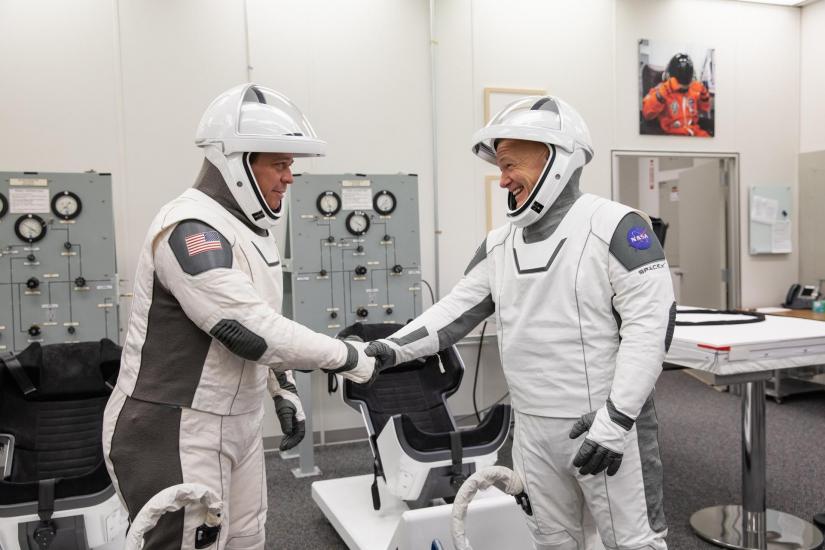 astronauts in white flight suit shake hands