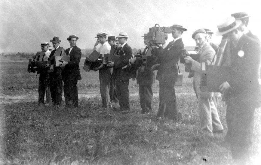 Black and white photo of photographers standing in a row. 