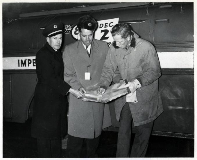 Three men in front of an airplane