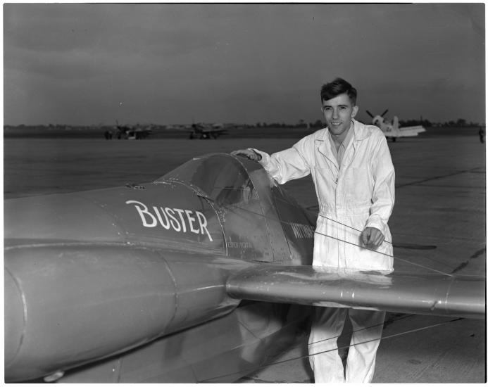 Man in white flight suit next to aircrat