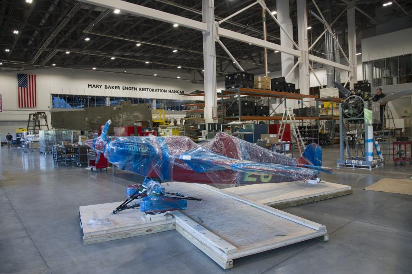 Red aircraft wrapped up in restoration hangar