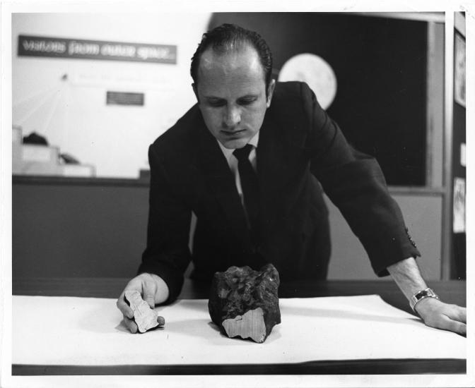 Man in suit looks at rock