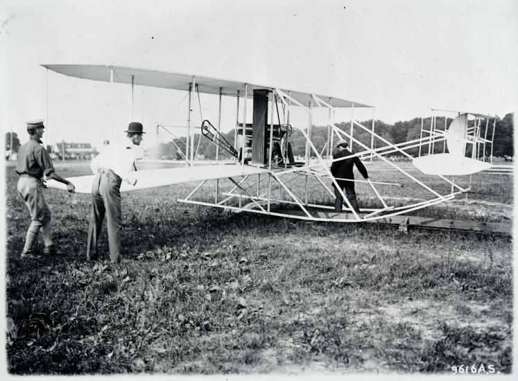 Black and white photograph of Wilbur Wright preparing his aircraft.