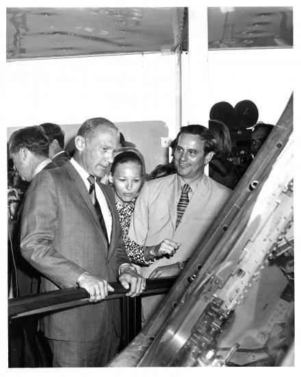 Three people gaze at spacecraft. 