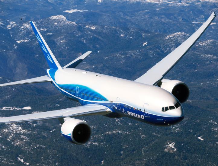 A commercial jet aircraft in flight. Jet features white and blue Boeing livery on the belly, sides of the fuselage, and tail.