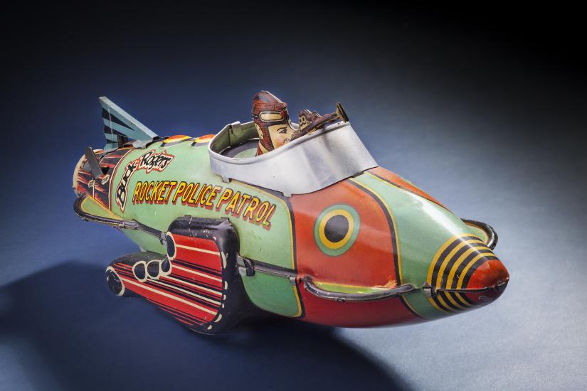 A red and light green police patrol rocket ship with a figure inside the open cockpit.