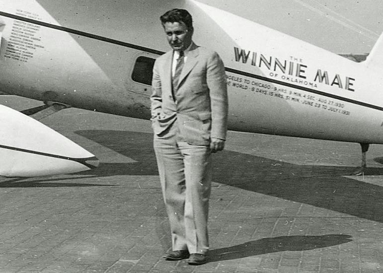 Wiley Post stands under the wing of his Winnie Mae aircraft.