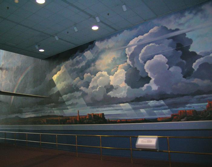 Partial view of mural of clouds above a desert environment, located inside the Museum.