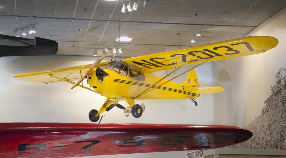 Yellow monoplane with one engine displayed as hanging in the Museum.