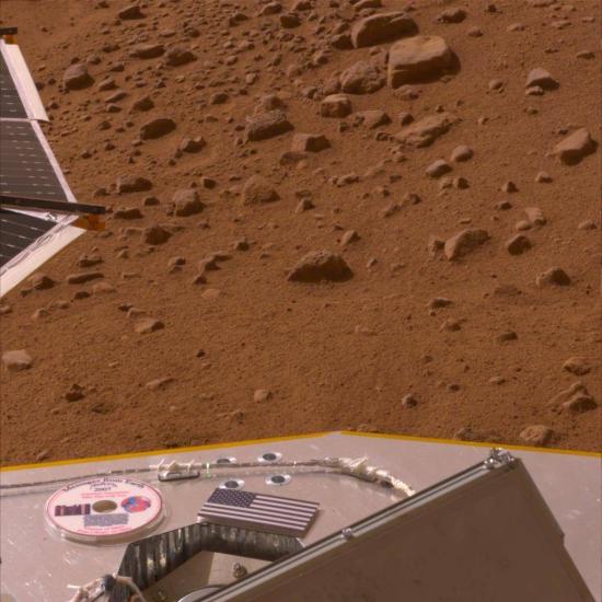 The American flag and a mini-DVD on the Phoenix's deck with Mars in the foreground.