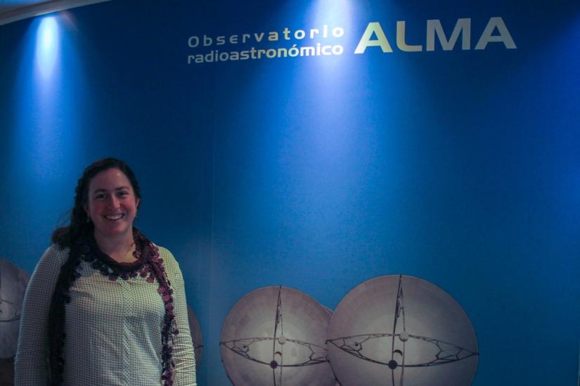 Image of Genevieve in front a sign for the ALMA observatory.