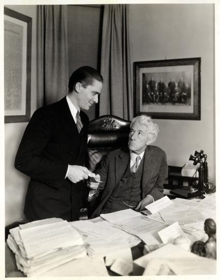 Two Men Exchange a Ticket Behind a Desk