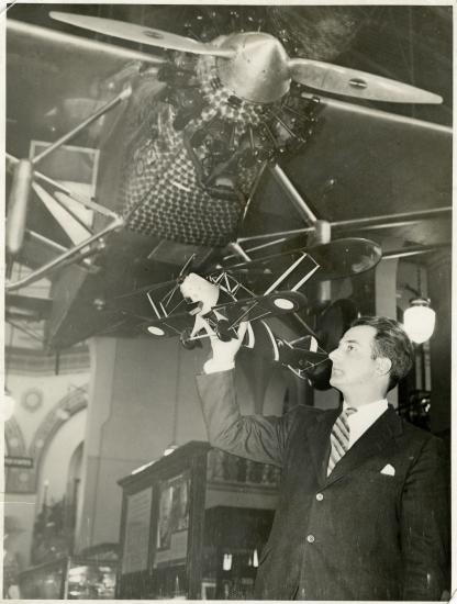 Man holding model of plane underneath hanging aircraft