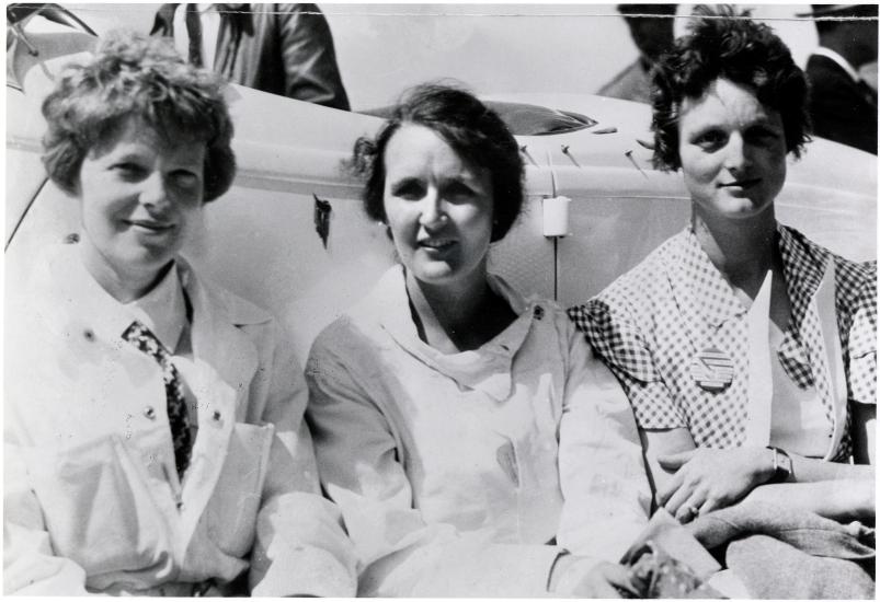 Earhart, Nichols, and Thaden sit shoulder to shoulder in this black and white photo.