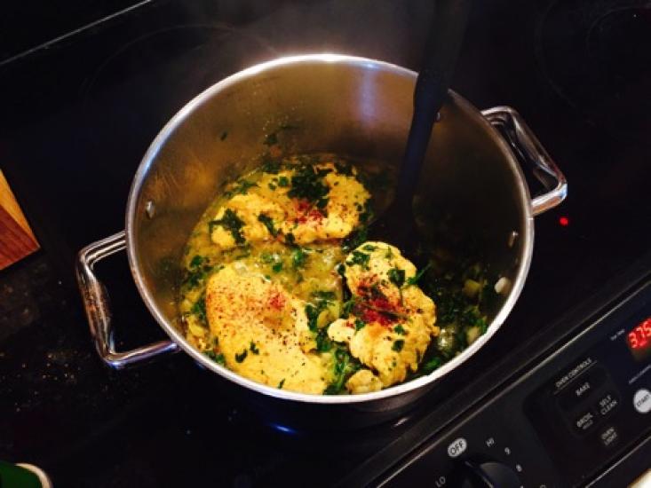 Chicken simmers in a pot on the stove.