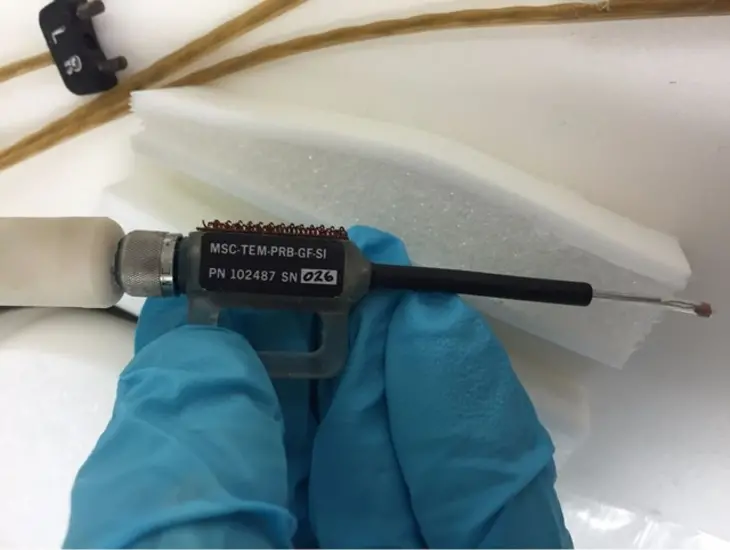 A device pinched between two gloved hands.