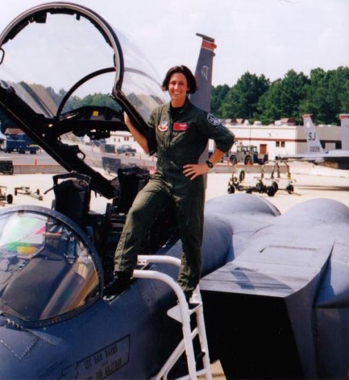 A woman stands outside a plane.