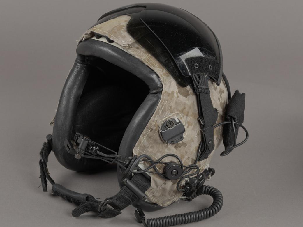 A flying helmet covered in camouflage and various wires.