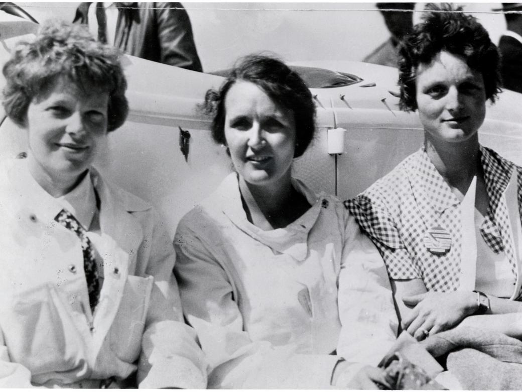 Earhart, Nichols, and Thaden sit shoulder to shoulder in this black and white photo.