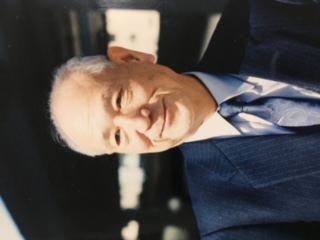 Morinaga smiling wearing a dark blue suit and blue tie.